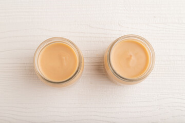 Baby puree with fruits mix, apple, banana infant formula in glass jar on white, flat lay