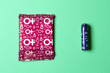 A sanitary napkin and a tampon lie on a green background. View from above. Gasket in red packaging. A tampon in a lilac package. Horizontal image. Flatley