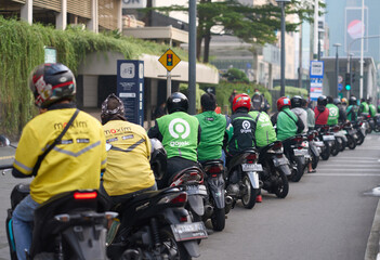 Motor cycle taxi drivers parking on the side of the Sudirman Road waiting for passengers
