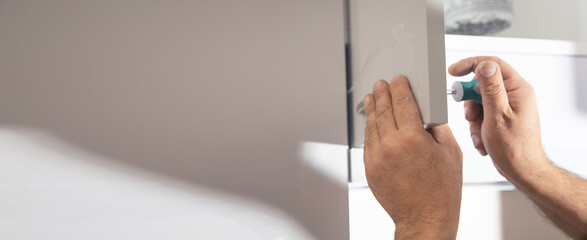  Worker fixing kitchen cabinet using screwdriver.