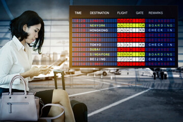 Asian businesswoman sitting at the airport with flight schedule in the background