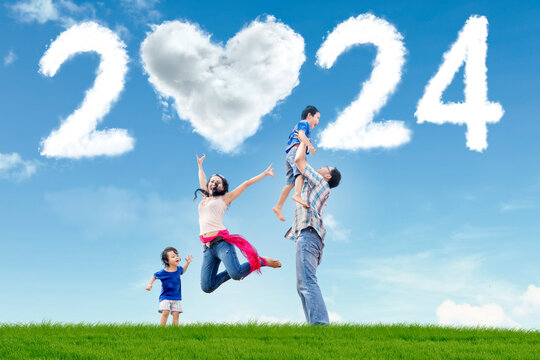 Happy family having fun in the park with heart shaped cloud of new year 2024