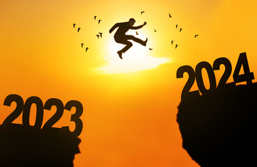 Caucasian businessman jump through the gap between hill to the new year of 2024