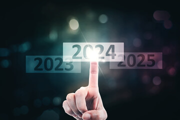 Close up of pointing finger pressing 2024 new year numbers on virtual screen