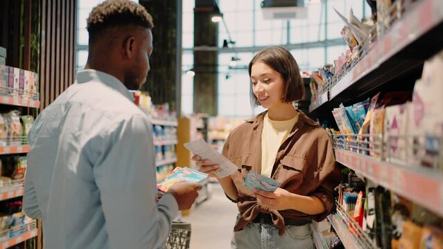 African American man and European woman take goods from shelf
