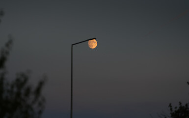 Ecological street light concept image. An LED lighting pole with the moon on top of it during moonrise. Street illumination.