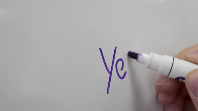 close-up of a man's hand with a blue marker writing the word "no" on a white board