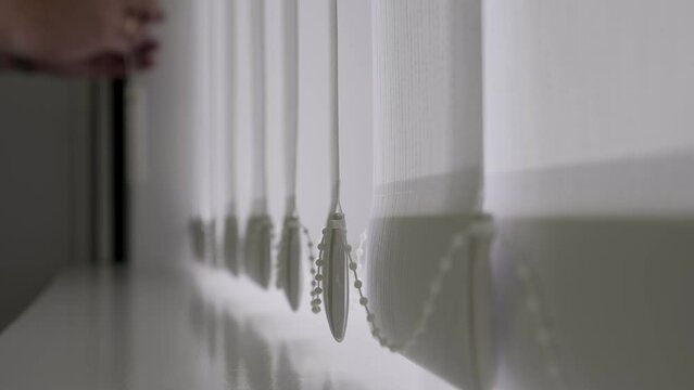 the concept of home comfort
close-up of a window in a home or office with white blinds
vertical light blinds are opened or retracted to create exactly the kind of lighting in the room as needed