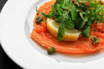 Salmon carpaccio, on a plate, with lemon, close-up