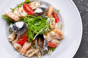 Seafood salad with mussels, squid, shrimp, on a round white plate, on a white plate, close-up
