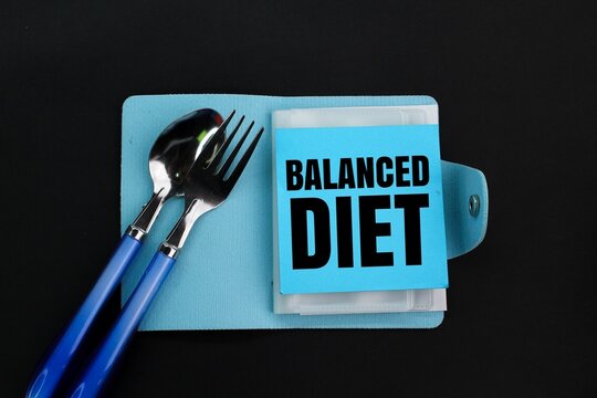 spoon, fork and book with the word balanced diet. the concept of nutritional balance or taking care of the body