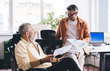 Caucasian financial experts discussing business documents during working time in office interior,...