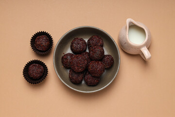 Brigadeiro in bowl and milk jug on beige background, top view