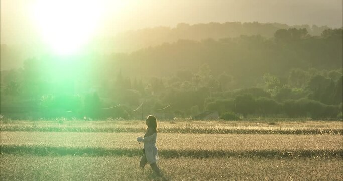 Chica andando por atardecer por el campo de trigo