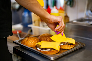 woman chef hand cooking burger with vegetables and meat on restaurant kitchen