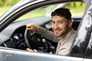 Profile view of handsome man driving his car on city street