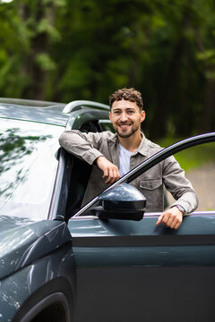 Smiling man standing next to his car on the street