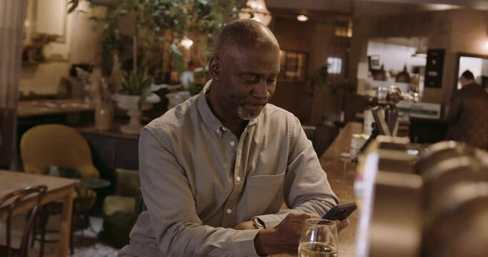 Senior Adult Male at Bar Looking at Phone  Waiting for Date