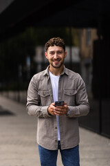 Confident young man using cell phone and drinking coffee in the city