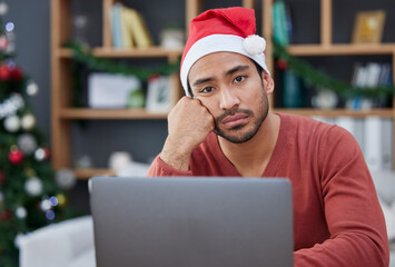 Bored, christmas hat and portrait of a tired man in the office with a laptop working on a project. Burnout, exhausted and young male creative designer with xmas decorations in the modern workplace.