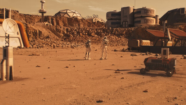 Two astronauts in space suits walk on Mars surface. Research station or scientific base. Exploring space mission on red planet. Future technologies. Futuristic colonization and exploration concept.