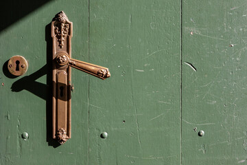 Ornate brass door handle on a green door