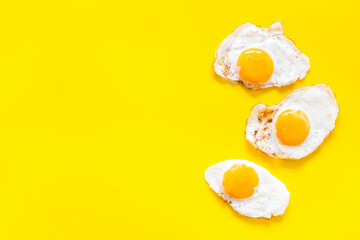 Fried eggs pattern on yellow background, top view. Breakfast concept