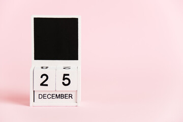Christmas, wooden calendar with the date December 25 on a pink background. Christmas and New Year celebration concept.