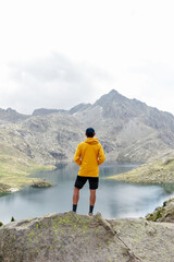Fototapeta premium Young man standing on a rock with mountain background