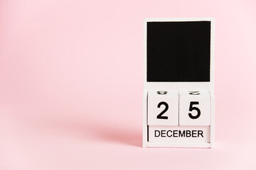 Christmas, wooden calendar with the date December 25 on a pink background. Christmas and New Year celebration concept.