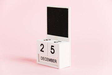 Christmas, wooden calendar with the date December 25 on a pink background. Christmas and New Year celebration concept.