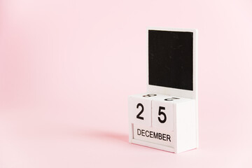 Christmas, wooden calendar with the date December 25 on a pink background. Christmas and New Year celebration concept.