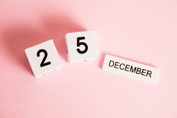 Christmas, wooden calendar with the date December 25 on a pink background. Christmas and New Year celebration concept.