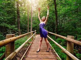 Teenager girl in elegant blue dress posing in a park during senior photo session. Fashion and glamour concept. Young lady model with slim body type. Beauty and style theme.