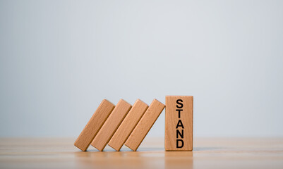 Wooden block stand stopping domino business crisis effect, Money coins heap still balance and stop the falling domino, financial stability concept