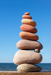 Rock zen pyramid of colorful pebbles on a background of blue sky