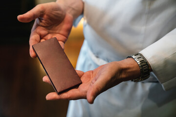 Chef holding a blank mockup of chocolate bar package on hands