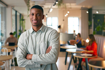 Fototapeta premium Portrait Of Smiling Businessman Standing In Busy Office 