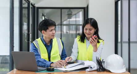 Two young man and woman engineers meeting, working, discussing, planing, designing, measuring layout of building blueprints in construction site floor at factory