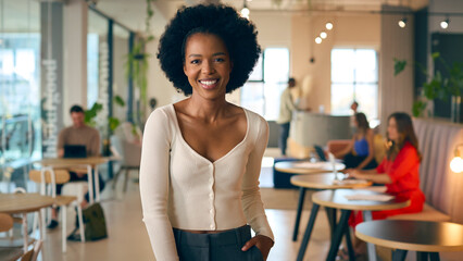 Portrait Of Smiling Businesswoman Standing In Busy Office 