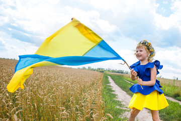 girl holding flag of Ukraine. Blue yellow flag of Ukraine with coat of arms in hands of child on...