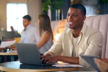 Fototapeta na wymiar Businessman Working On Laptop In Informal Seating Area Of Modern Office