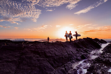 Surfers standing on Currumbin Rock at sunrise. Gold Coast Australia.