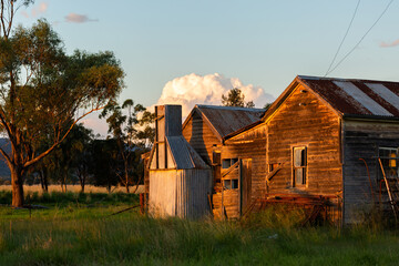 last sunset light hitting old dilapidated wooden shack on rural australian farm
