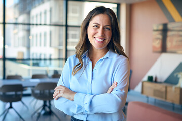 Portrait Of Smiling Mature Businesswoman Standing In Empty Office 