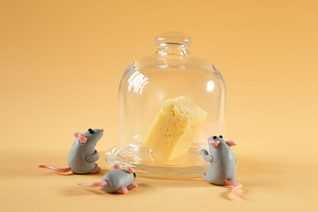 Little plasticine gray mice look at an inaccessible piece of cheese.