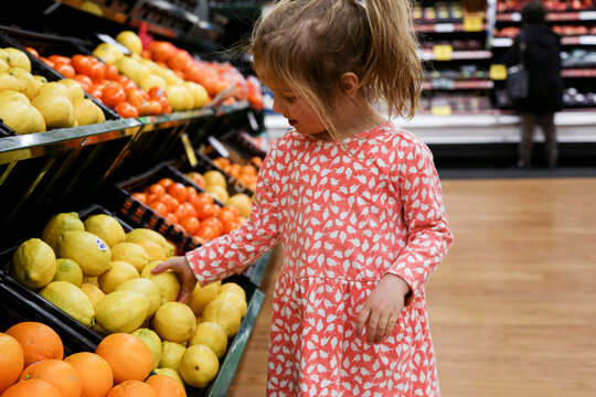 Young Girl Picking Fruits in Supermarket