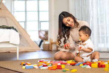 Portrait of enjoy happy love asian family mother with little asian baby smiling activity learn and skill brain training play with toy build wooden blocks board education game at home