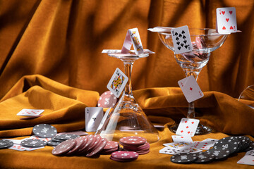 Composition of cocktail glasses and playing cards on brown velvet fabric. Composition of casino stuff