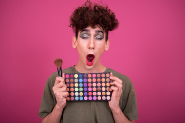 lgbt culture. Funny guy doing makeup. Pink background.